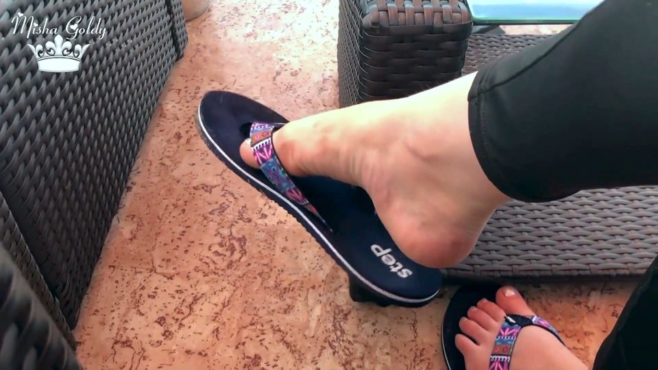 Flip flops dangling outdoor near lake with silver nails & toes wiggling