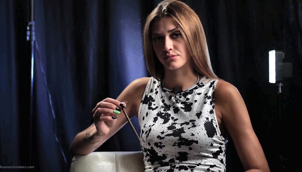 Slim Brunette in a Patterned Dress Smoking Slowly with a Calm and Confident Attitude